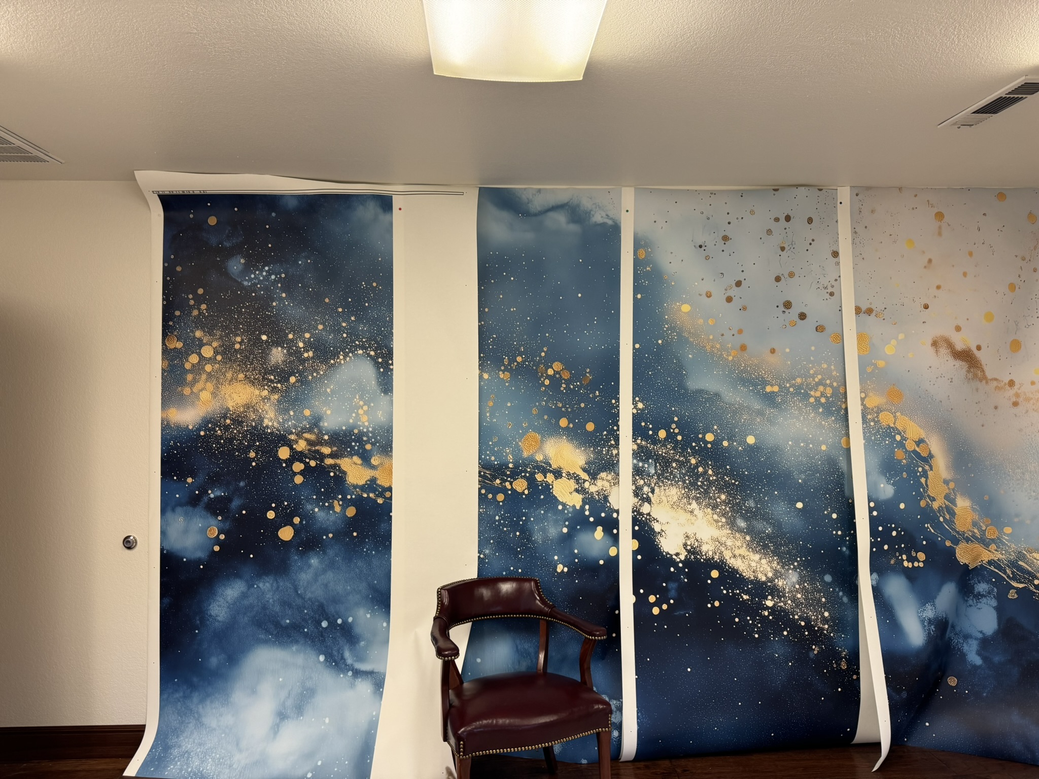 Indigo and gold mural panels positioned on the wall during installation