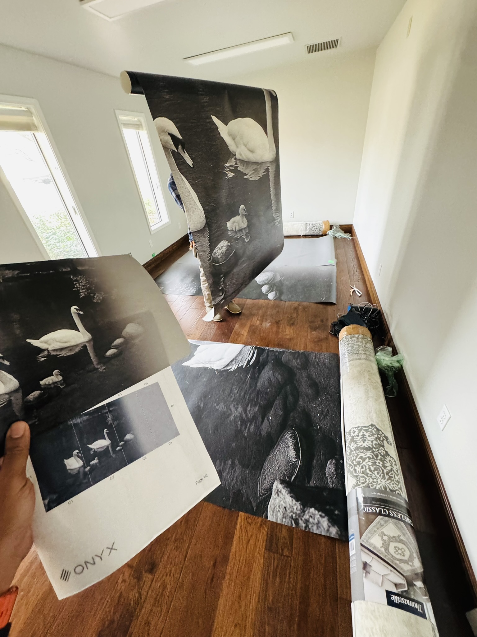 Installer checking the printed swan mural panels against the layout guide